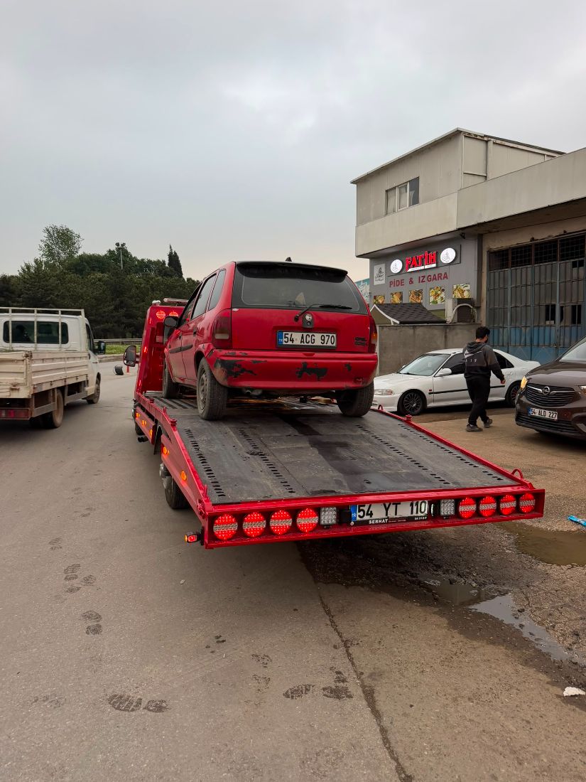 Kırmızı platformlu çekici üzerinde araç